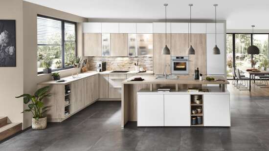 Helle, moderne Küche mit einer Kombination aus Holz- und Weißschränken, einer Kücheninsel und großen Fenstern mit Blick auf einen Garten.