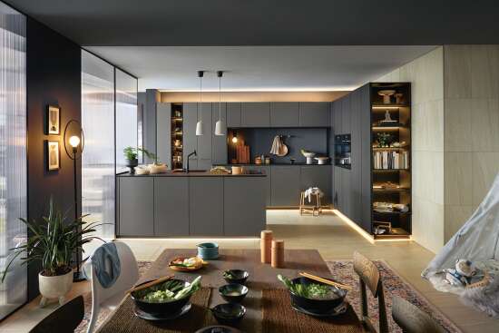 Stilvolle Küche in dunklen Tönen mit integrierter Beleuchtung, grauen Schränken, Kücheninsel, Essbereich mit gedecktem Tisch und Dekorationen.